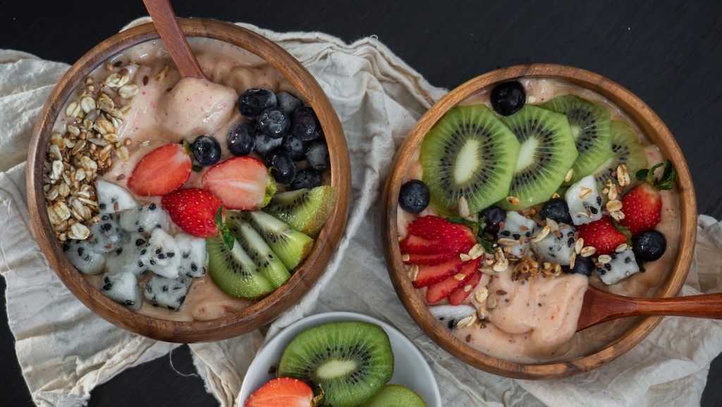 corta o kiwi e os mirtilos numa tigela de madeira